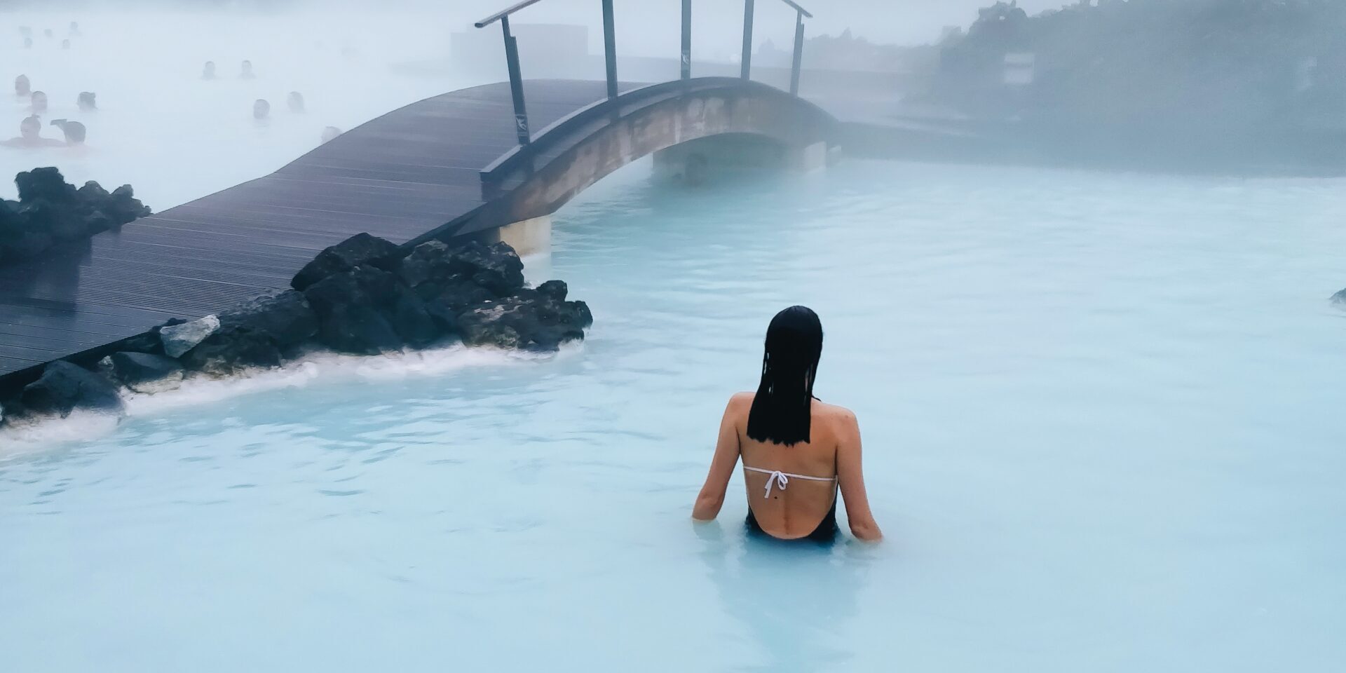 Vertical shot of a female swimming in a hot pool near the bridge