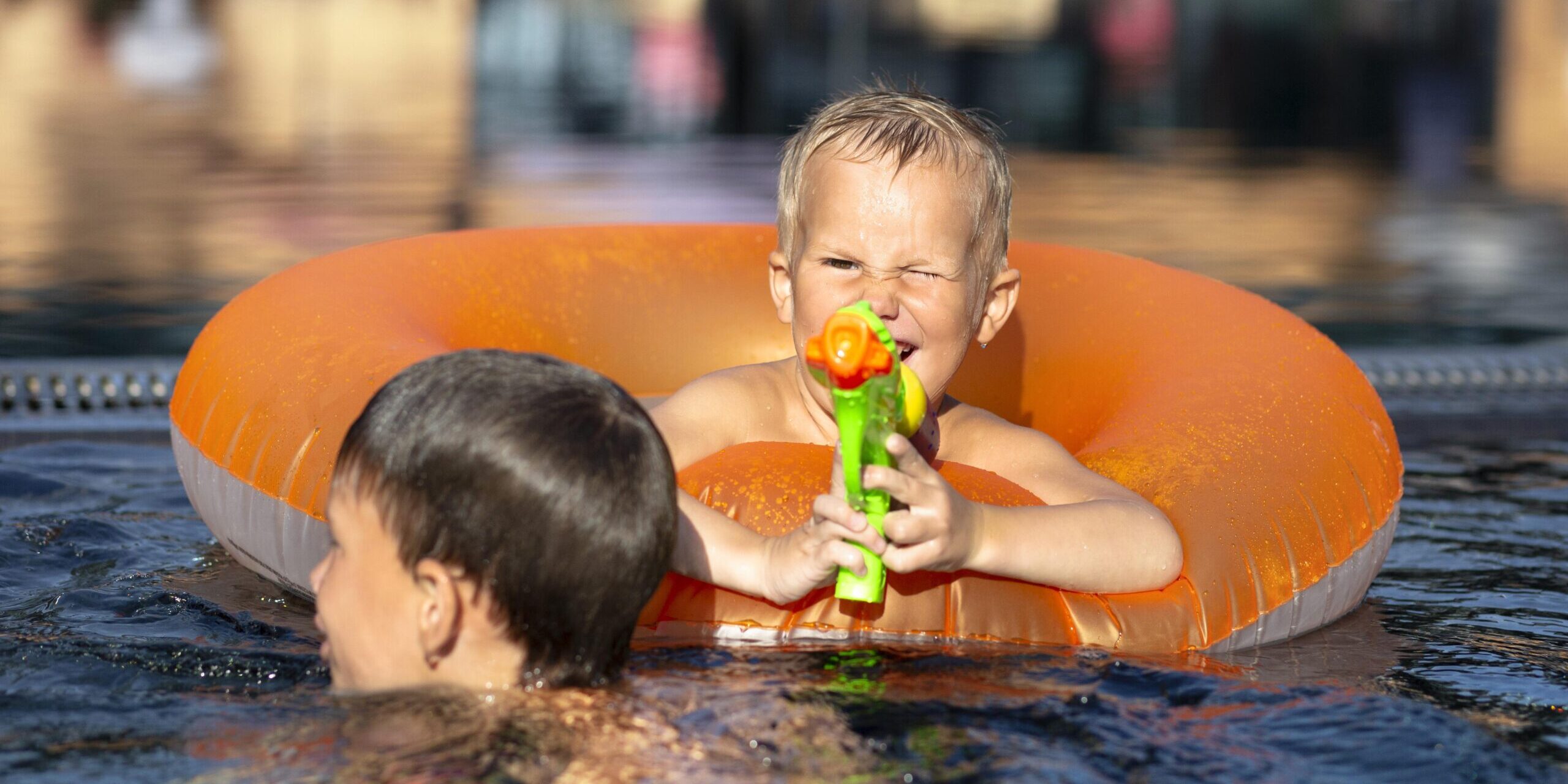boys-having-fun-swimming-pool-with-pool-float-water-gun
